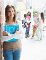 Pretty student smiling and holding notepads