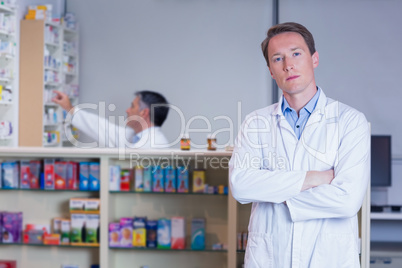 Unsmiling pharmacist standing with arms crossed