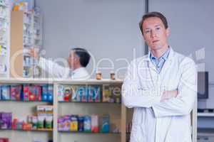 Unsmiling pharmacist standing with arms crossed