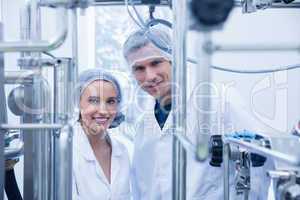 Scientist team behind metal gauge looking at camera