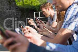 Happy students sitting in a row texting