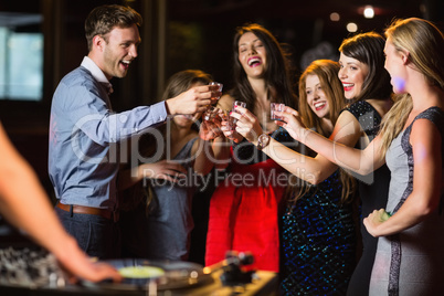 Happy friends drinking shots by the dj booth