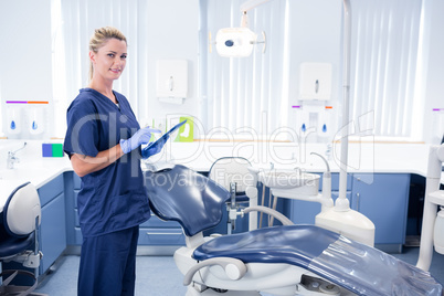 Smiling dentist working on tablet pc and looking at camera