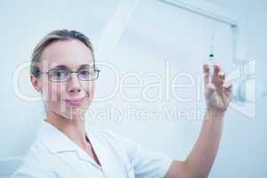 Smiling female dentist holding injection