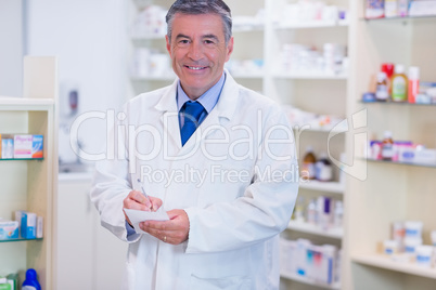 Portrait of a smiling pharmacist writing down notes