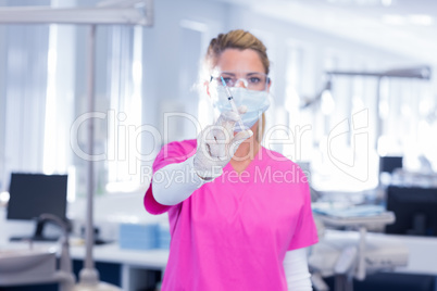 Dentist in surgical mask and scrubs holding syring
