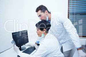 Concentrated dentists looking at x-ray on computer