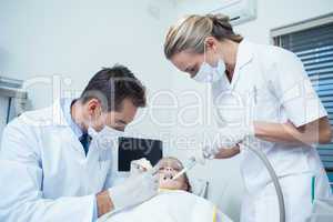 Male dentist  with assistant examining girls teeth