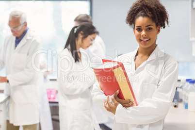 Science student holding large folder in lab