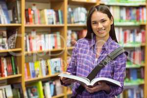 Smiling university student holding textbook