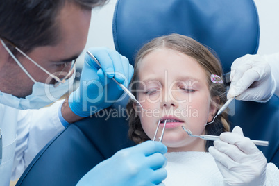 Dentist with assistant examining girls teeth