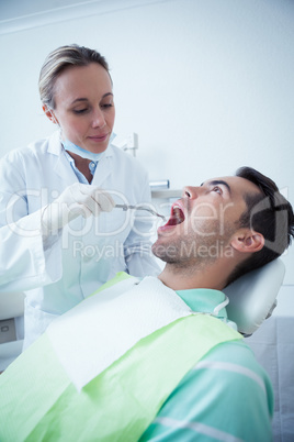 Female dentist examining mans teeth