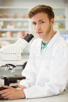 Young scientist working with microscope