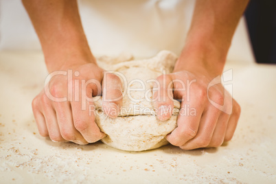 Baker kneading dough at a counter