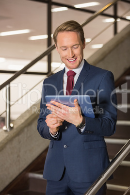Handsome businessman standing on steps using tablet