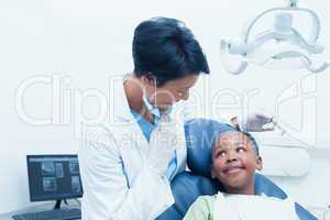 Portrait of smiling female dentist examining boys teeth