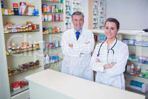 Smiling pharmacist and his trainee with arms crossed