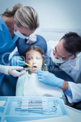 Dentist with assistant examining girls teeth