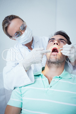 Female dentist examining mans teeth