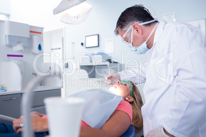 Dentist in surgical mask examining a patients teeth