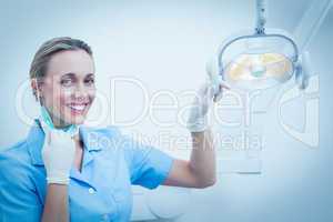 Smiling female dentist adjusting light