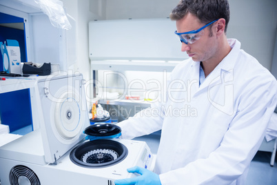 Chemist wearing safety glasses and using a centrifuge