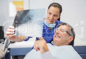 Smiling dentist showing x-ray to her patient