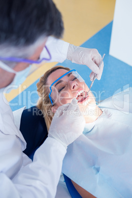 Dentist examining a patients teeth in the dentists chair