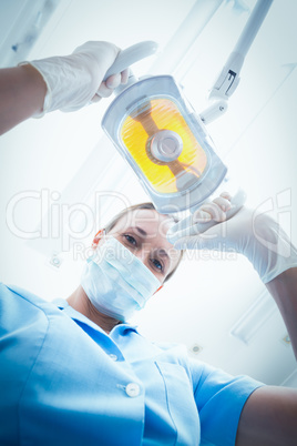 Portrait of female dentist adjusting light