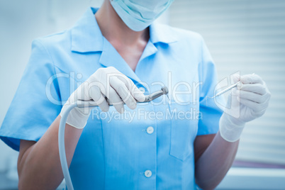 Mid section of dentist holding dental tools