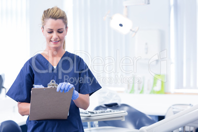 Smiling dentist writing in clipboard