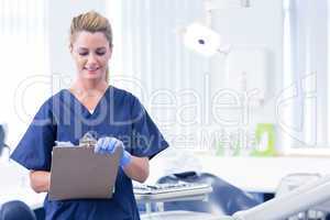 Smiling dentist writing in clipboard