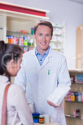 Smiling pharmacist holding a paper bag looking at camera