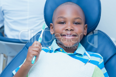 Boy holding toothbrush in the dentists chair