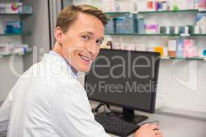 Happy pharmacist using the computer