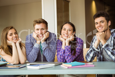 Smiling students studying together and look at camera