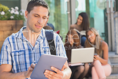 Happy student using his tablet pc on campus