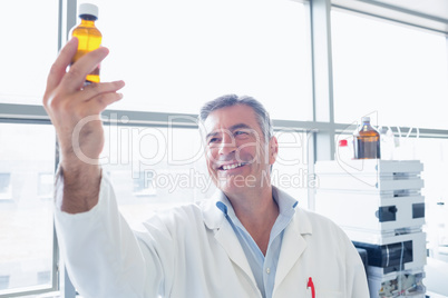 Smiling scientist in lab coat holding a chemical bottle