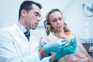 Male dentist teaching woman how to brush teeth