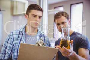 Two men looking at the beaker with beer