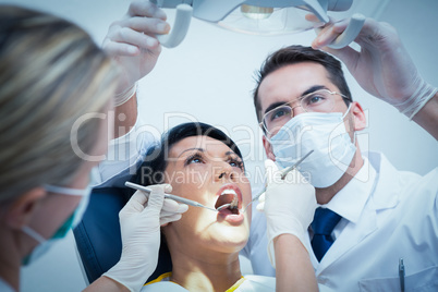 Dentist with assistant examining womans teeth