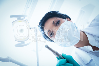 Female dentist in surgical mask holding dental drill