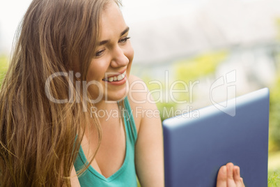 Smiling university student lying and using tablet pc Smiling university student lying and using tablet pc