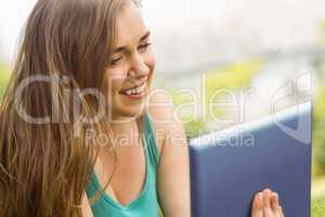 Smiling university student lying and using tablet pc