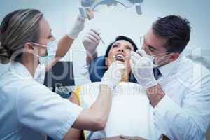 Dentist with assistant examining womans teeth