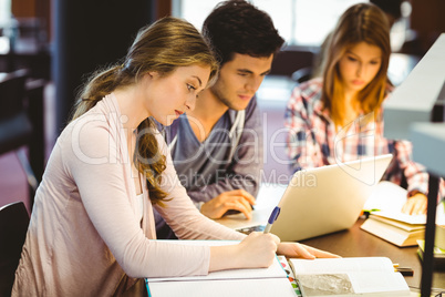 Focused classmates studying together and using laptop