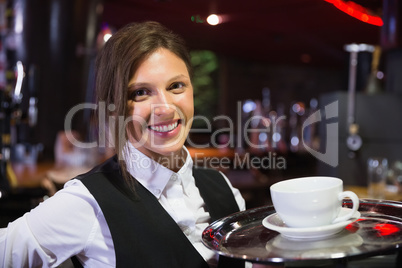 Happy barmaid holding tray with coffee