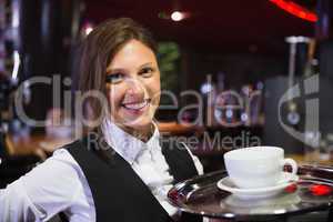 Happy barmaid holding tray with coffee