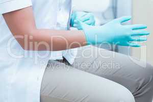 Mid section of dentist wearing surgical glove