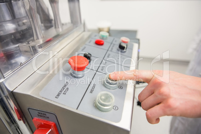 Pharmacist pressing button on machine